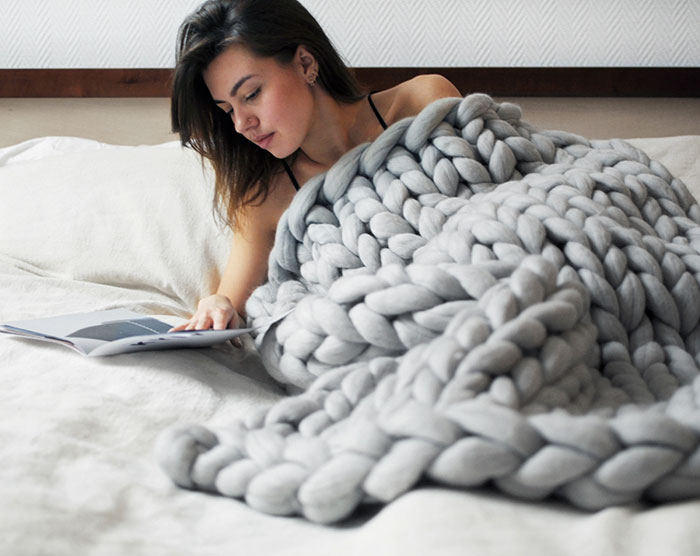 coperta in filato gigante grigia e ragazza a letto che legge