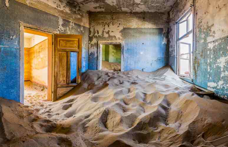 immagine di interno di una casa a Kolmanskop sommersa dalla sabbia