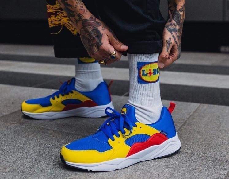 scarpe da ginnastica Lidl nei colori blu rosso e giallo con calzino bianxo e logo lidl