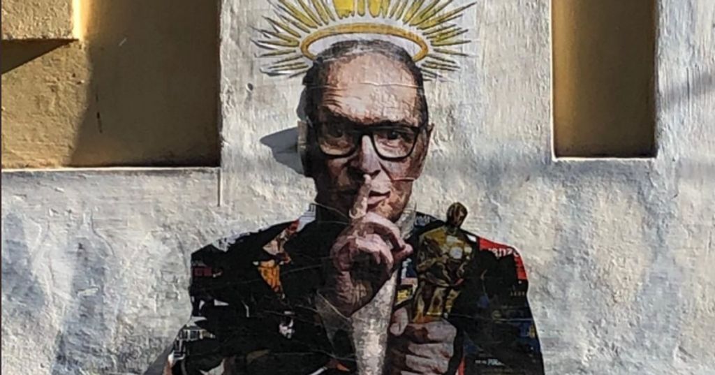 murale che ritrae ennio morricone con l'oscar in mono e il gesto di fare silenzio con l'altra mano