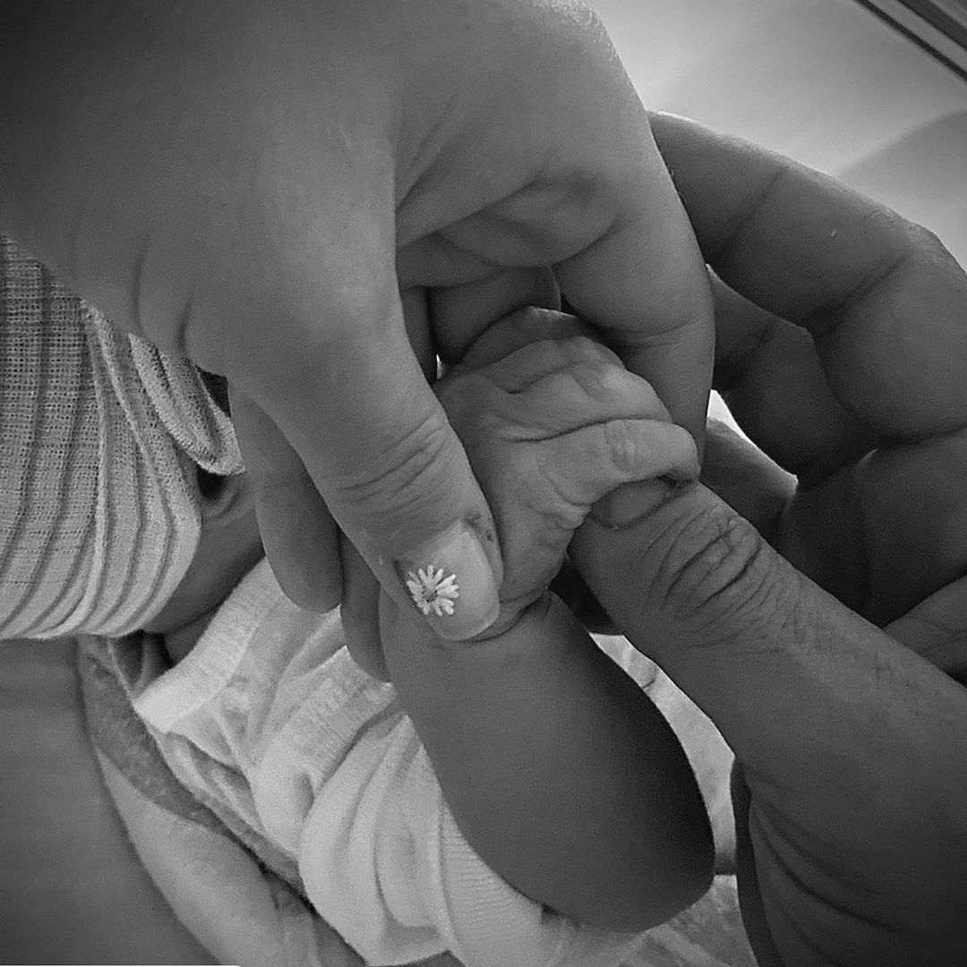 immagine in bianco e nero con due mani di adulto e una di neonato la diglia di Katy Perry e Orlando Bloom