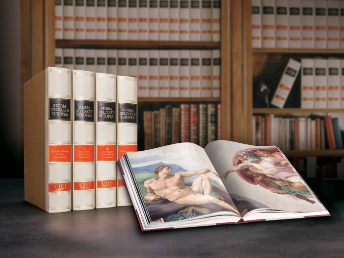 Utet grandi opere un libro aperto e alcuni cataloghi di pregio, sullo sfondo una libreria