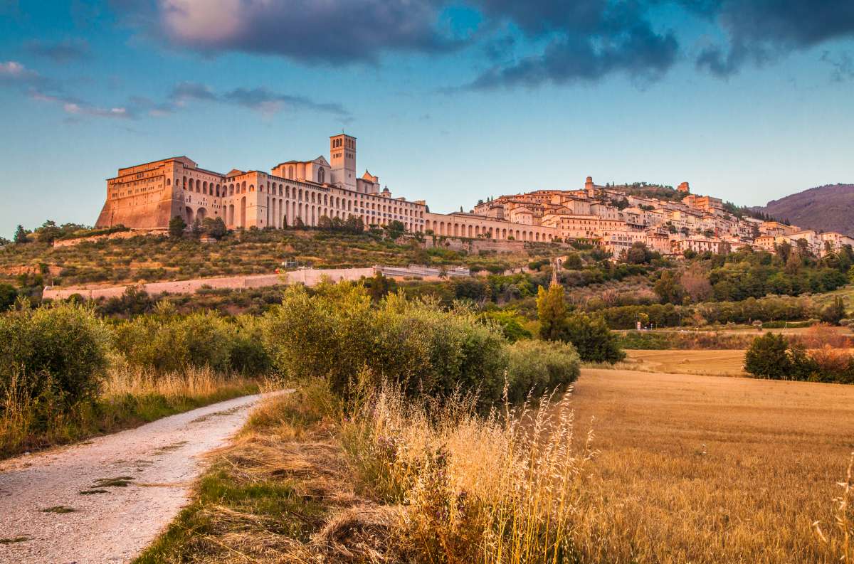 Foto panoramica di Assisi al tramonto con la Basilica di San Francesco in primo piano